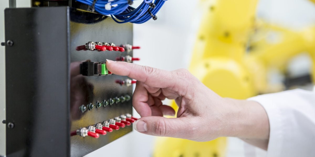 Close-up of woman switching on switch in factory